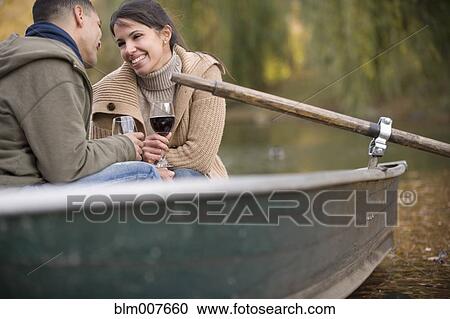 Stock Image - Couple drinking red wine in rowboat. Fotosearch