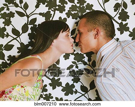 Stock Image - Couple face to face in front of wallpaper. Fotosearch