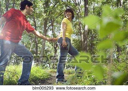 Stock Image - Couple holding hands in forest. Fotosearch