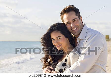 Stock Image - Couple hugging on beach. Fotosearch