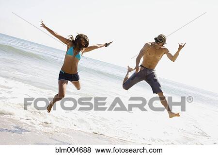 Stock Photo - Couple jumping on beach together. Fotosearch