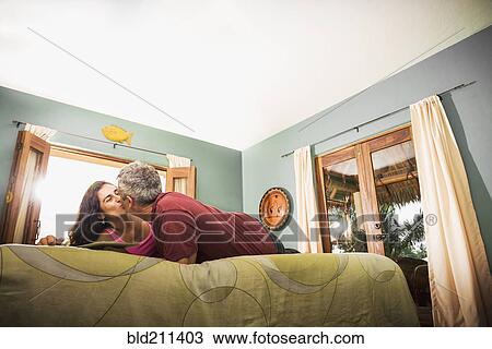 Stock Image - Couple kissing on bed. Fotosearch