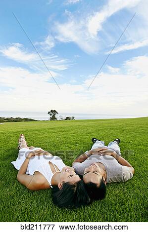 Stock Photo - Couple laying in grass in rural landscape. Fotosearch