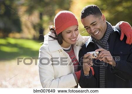 Couple looking at digital photographs on camera View Large Photo Image Stock Photo - Couple looking at digital photographs on camera. Fotosearch