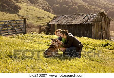 Couple petting dog in rural landscape View Large Photo Image Stock Photo - Couple petting dog in rural landscape. Fotosearch
