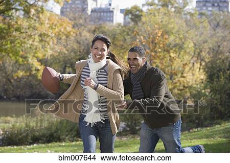 Picture - Couple playing football in park. Fotosearch