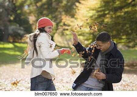 Couple playing in autumn leaves in park View Large Photo Image Stock Image - Couple playing in autumn leaves in park. Fotosearch