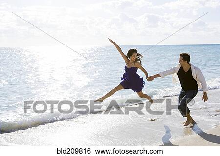 Couple playing in surf on beach View Large Photo Image Stock Photograph - Couple playing in surf on beach. Fotosearch
