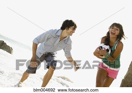 Stock Image - Couple playing with soccer ball on beach. Fotosearch