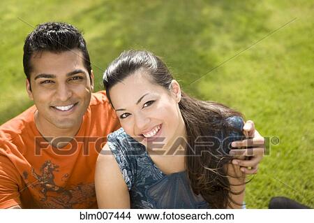 Couple sitting on grass and hugging View Large Photo Image Picture - Couple sitting on grass and hugging. Fotosearch
