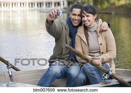 Couple taking self-portrait in rowboat View Large Photo Image Stock Photo - Couple taking self-portrait in rowboat. Fotosearch