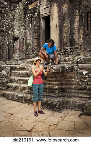 Stock Image - Couple visiting ancient temple, Angkor, Siem Reap, Cambodia. Fotosearch