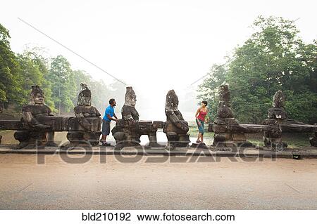 Stock Image - Couple visiting ancient temple, Angkor, Siem Reap, Cambodia. Fotosearch