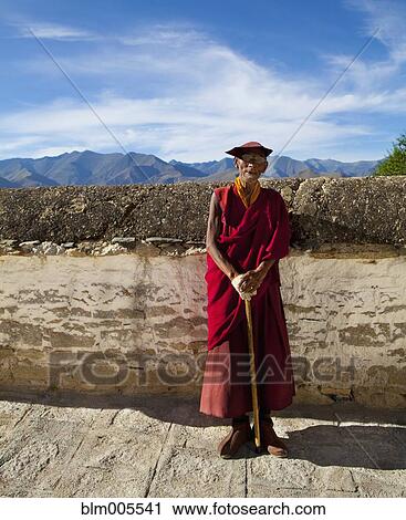 Stock Image - Elderly Tibetan monk with walking stick. Fotosearch