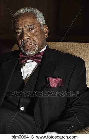 Stock Image - Elegant African American man sitting in chair. Fotosearch