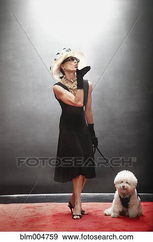 Stock Photo - Elegant Caucasian woman with dog blowing kisses on red carpet. Fotosearch