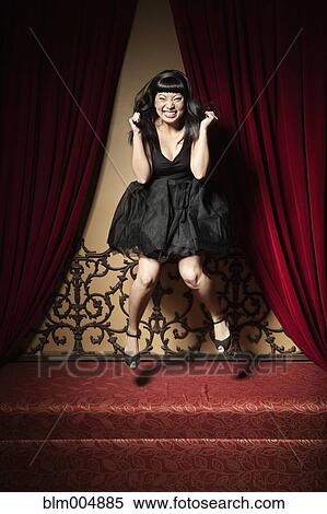 Stock Photography - Elegant Chinese woman jumping on ornate sofa. Fotosearch