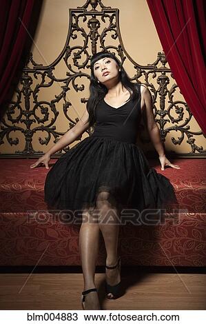 Stock Image - Elegant Chinese woman sitting on ornate sofa. Fotosearch