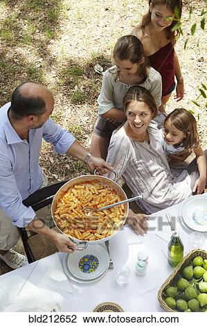 Family eating together at table outdoors View Large Photo Image Stock Image - Family eating together at table outdoors. Fotosearch