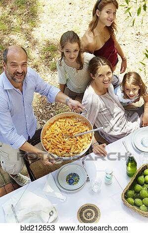 Family eating together at table outdoors View Large Photo Image Stock Image - Family eating together at table outdoors. Fotosearch