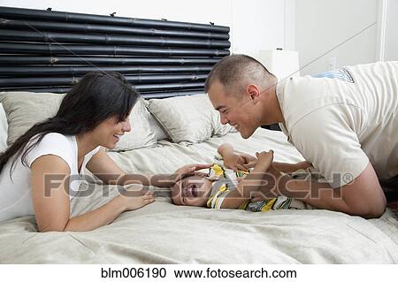 Family playing on bed in bedroom View Large Photo Image Stock Image - Family playing on bed in bedroom. Fotosearch