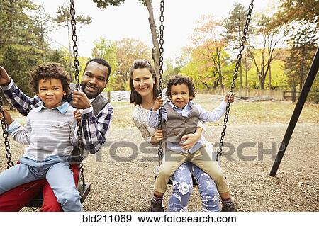 Family sitting on swings in park View Large Photo Image Stock Photo - Family sitting on swings in park. Fotosearch