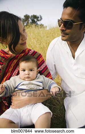 Picture - Family sitting together in field. Fotosearch