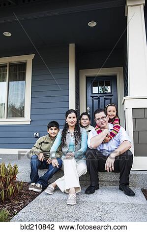 Stock Image - Family smiling on front stoop. Fotosearch
