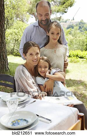 Family smiling together at table outdoors View Large Photo Image Stock Image - Family smiling together at table outdoors. Fotosearch