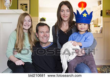 Stock Image - Family smiling together in living room. Fotosearch
