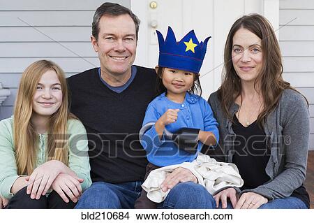 Picture - Family smiling together outside house. Fotosearch