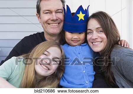 Stock Photograph - Family smiling together outside house. Fotosearch