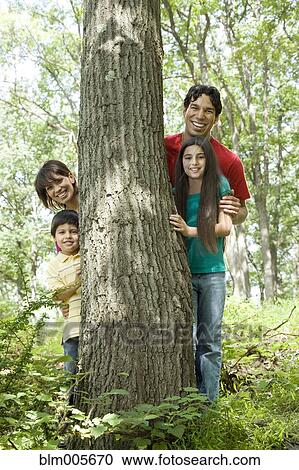 Family standing by tree trunk in forest View Large Photo Image Stock Image - Family standing by tree trunk in forest. Fotosearch