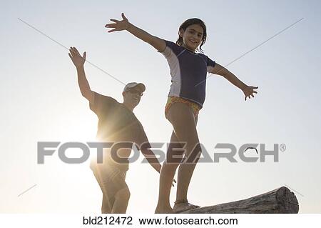 Stock Image - Father and daughter balancing on log. Fotosearch