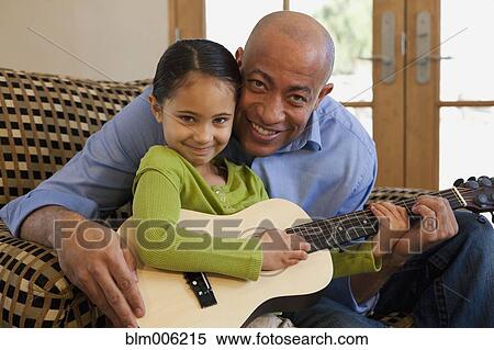 Stock Photography - Father and daughter playing guitar together. Fotosearch