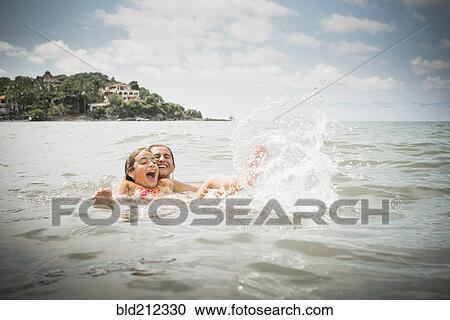 Stock Image - Father and daughter playing in lake. Fotosearch