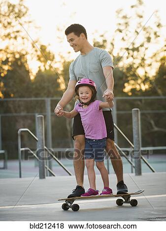 Father and daughter riding skateboard in park View Large Photo Image Stock Photo - Father and daughter riding skateboard in park. Fotosearch