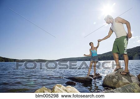 Stock Photo - Father and daughter standing by lake. Fotosearch