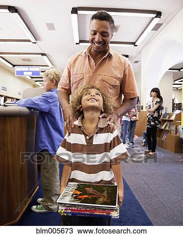 Stock Image - Father and son checking out books from library. Fotosearch