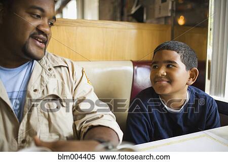 Stock Photography - Father and son sitting at diner booth. Fotosearch