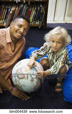 Stock Photo - Father and son with globe in library. Fotosearch