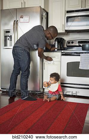 Stock Image - Father and toddler son in kitchen. Fotosearch