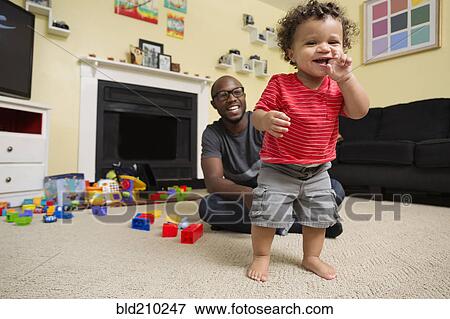 Stock Photo - Father and toddler son playing in living room. Fotosearch
