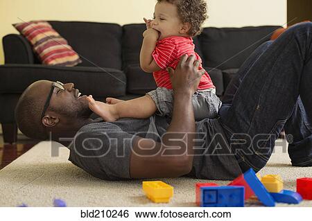 Father and toddler son playing in living room View Large Photo Image Stock Photograph - Father and toddler son playing in living room. Fotosearch