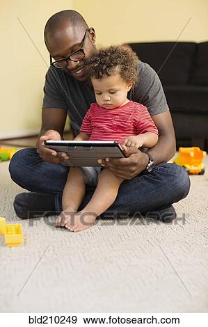 Stock Photo - Father and toddler son using digital tablet. Fotosearch