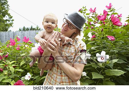 Stock Image - Father carrying baby daughter in park. Fotosearch