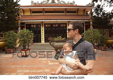Stock Photography - Father carrying baby girl in courtyard. Fotosearch