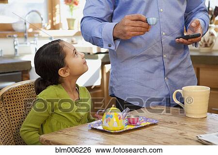 Stock Photograph - Father having tea party with daughter in kitchen. Fotosearch