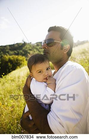 Picture - Father holding baby in field. Fotosearch