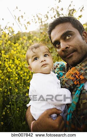 Stock Image - Father holding baby in field. Fotosearch
